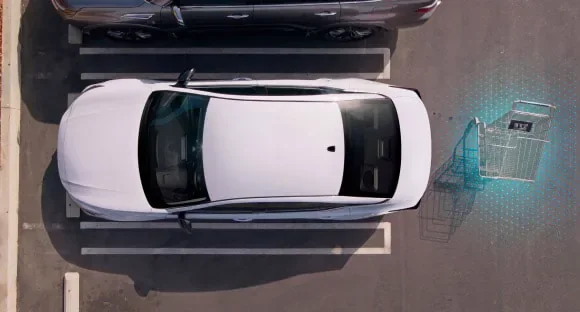 Top view of a white 2027 Nissan Altima in a parking lot with rear sensors detecting a shopping cart behind it at Nissan of Dearborn in Dearborn MI